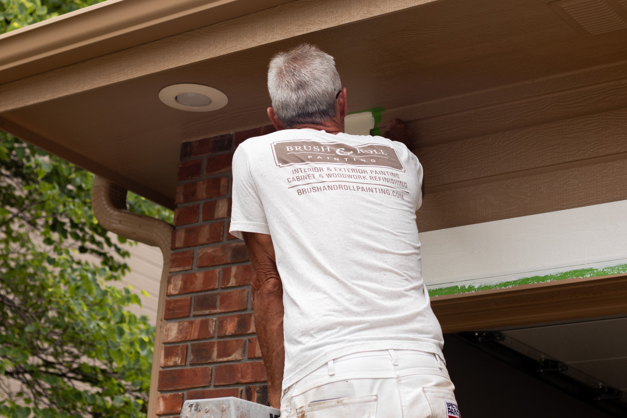 Brush & Roll Painting painter applying paint to exterior of house in Omaha, Nebraska.