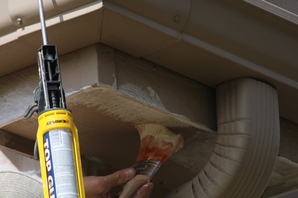 Primer being applied to top of corner of exterior of house in Omaha, NE.
