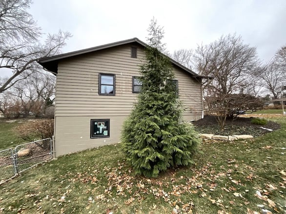 Exterior of house showing delaminating siding and paint peeling.