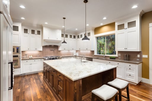 Wood Island with white painted cabinets in a large kitchen.