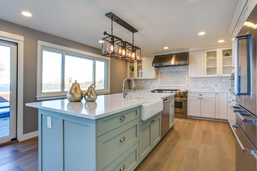 Kitchen with white cabinets and a light green island in the center of the room.