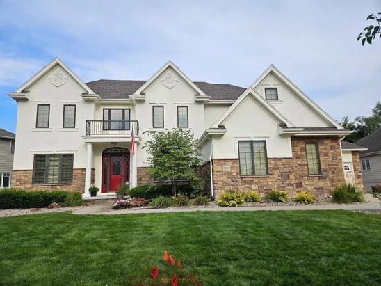 Exterior of home with white painted siding, black window trim, and beige stone on the bottom half of the home in Blair, NE.