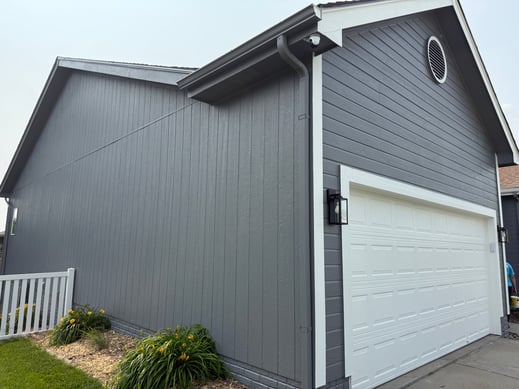 Exterior of house painted a darker grey with white trim and garage door.