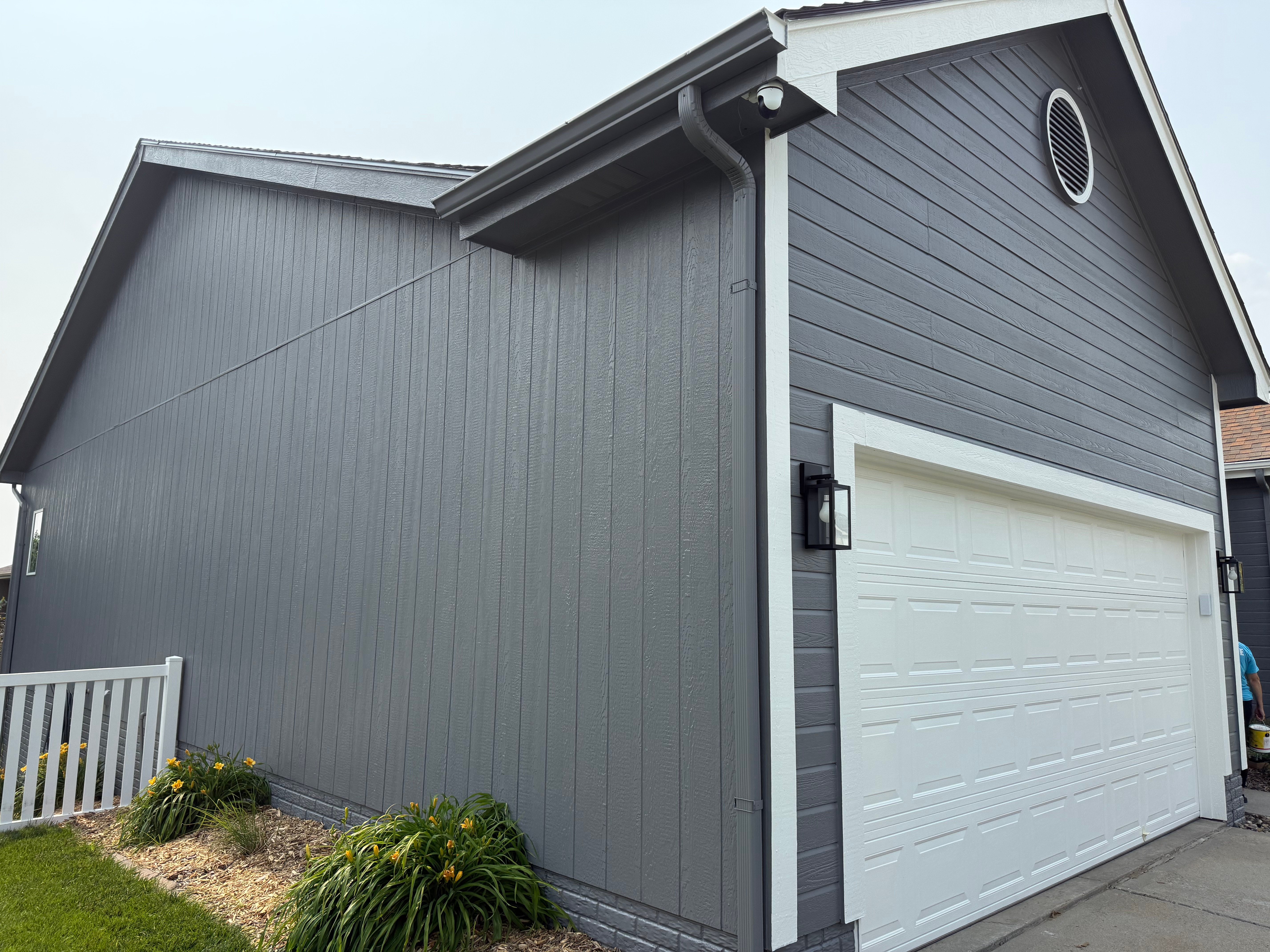 Grey exterior siding painted in Omaha, NE with white trim and garage doors and black accents.