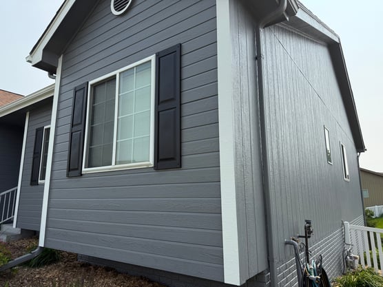 Exterior of house with dark grey paint and black shutters with white trim and window trim.