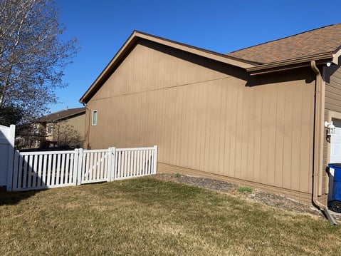 Light brown siding on a house that has faded and needs repainted.