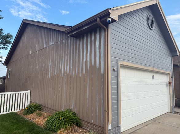 Exterior of house with primer and caulk on the outside before spraying dark grey paint.