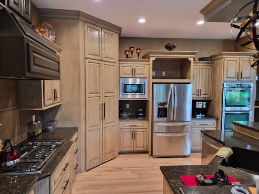 Kitchen with cabinets painted white with a darker glaze brushed over the surfaces with black handles.