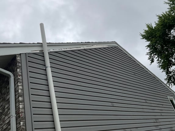Side of exterior of house with white paint peeling off metal galvanized steel trim.