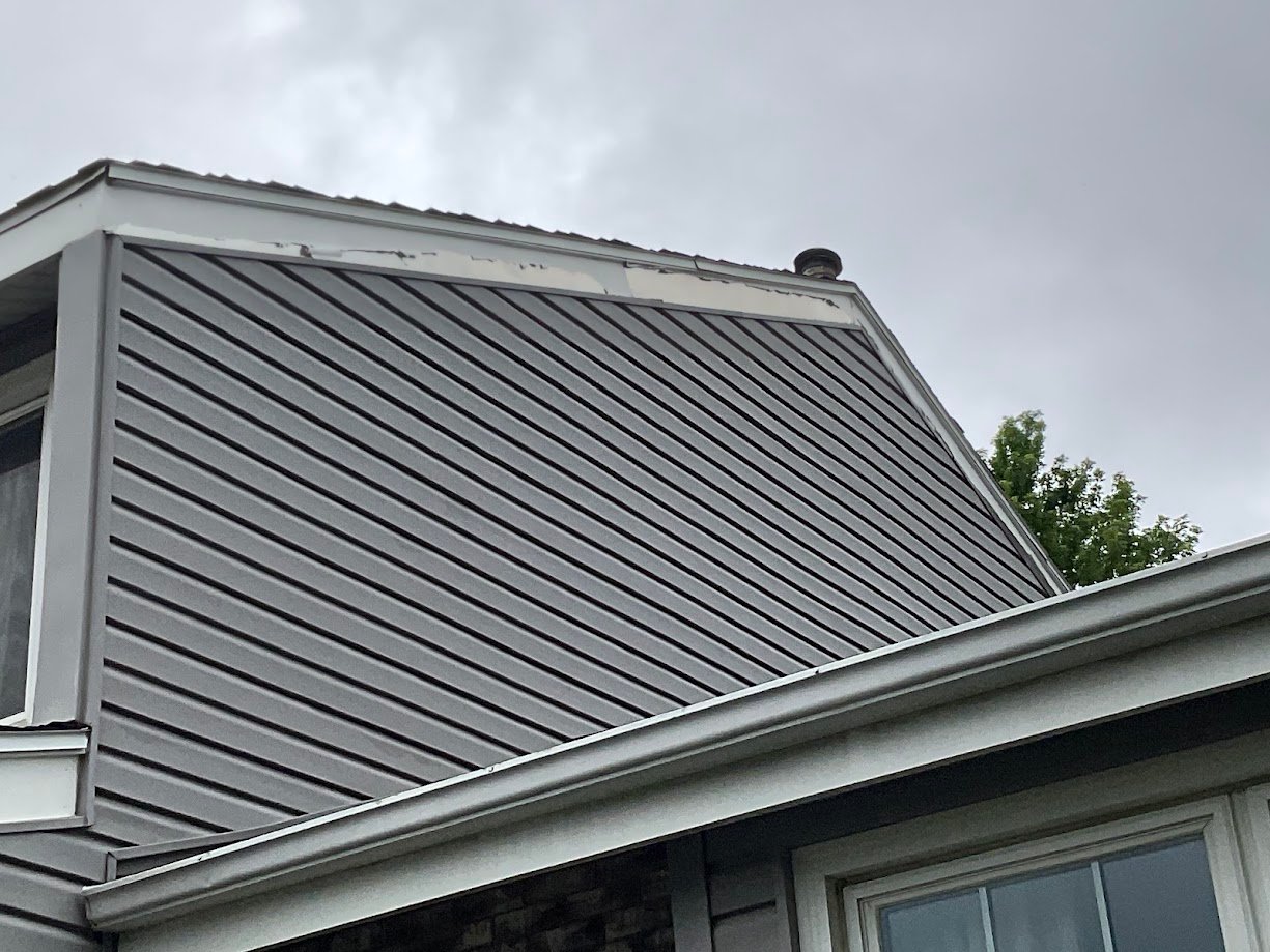 Galvanized steel trim painted white peeling off at the peak of a house in Omaha.