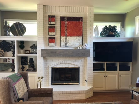 White brick fireplace in the middle of a wall in a living room.