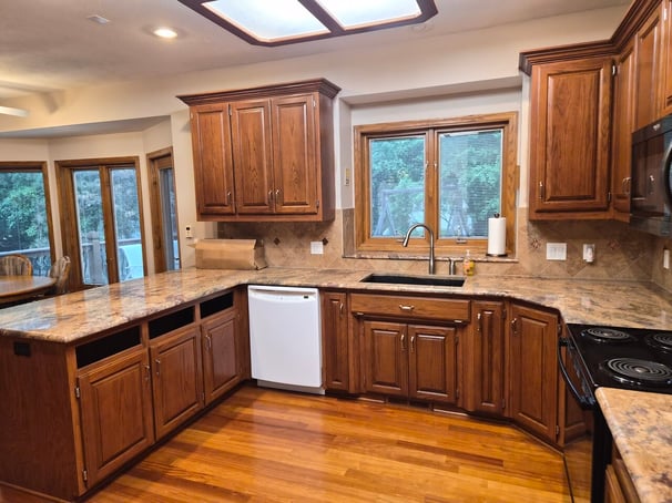 Kitchen with cabinets stained a warm brown color with warm countertops and floors.