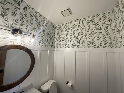 Wallpaper in bathroom on top half of interior walls with white board and batten on bottom half.