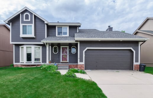 Exterior of home painted navy with white trim and bright green front lawn.