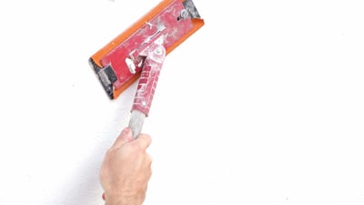 Painter sanding wall with pole sander.
