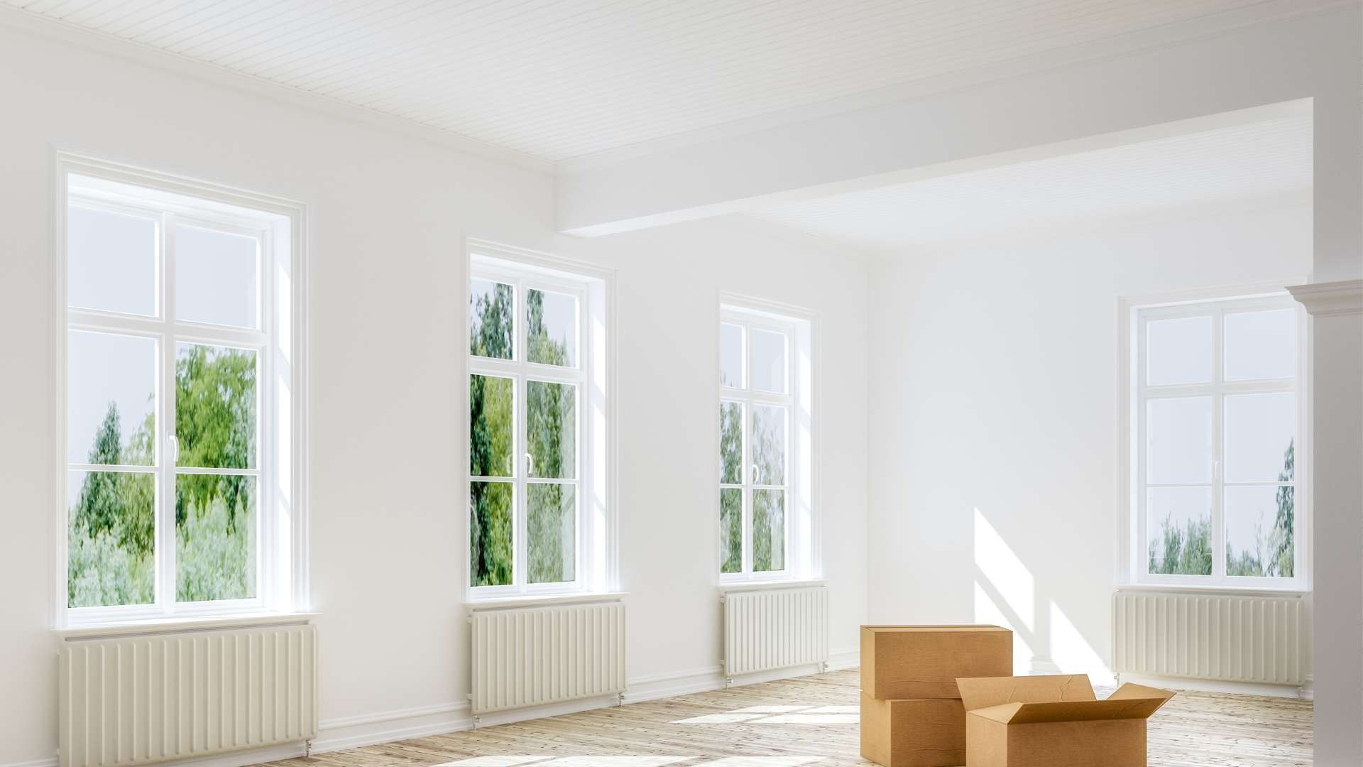 Empty living room with white walls and windows and 3 boxes. 