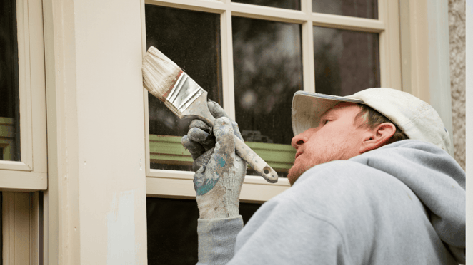 Painter painting window trim outside of a home in Omaha, NE.