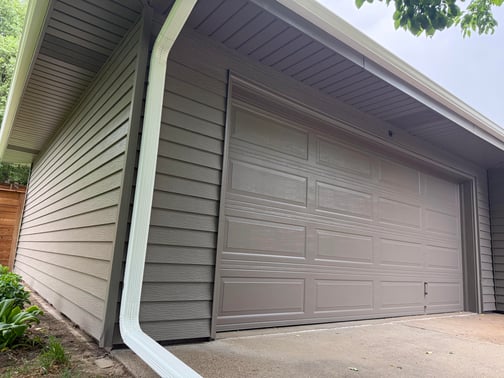 Garage painted the same color as the house with a white gutter.
