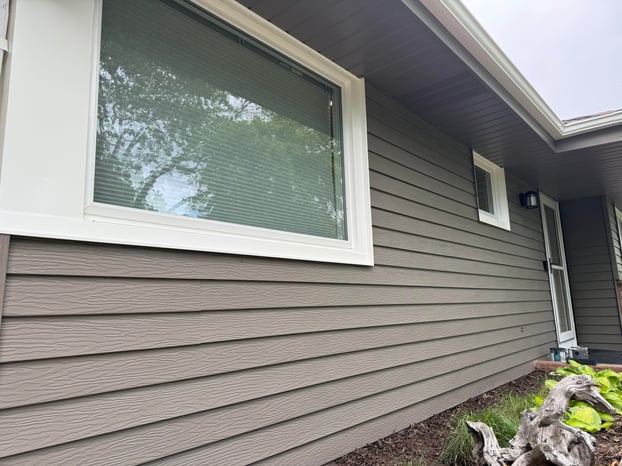 Outside siding on house painted a darker brown color with white trim on windows.