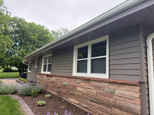 Exterior house with half of the wall stone and the other half painted siding in a dark brown color.
