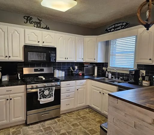 Cabinets painted white with black countertop and backsplash in a kitchen in Bellevue.