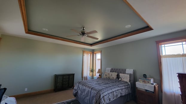 Bedroom painted with sage green walls and part of a ceiling painted white with golden oak woodwork.