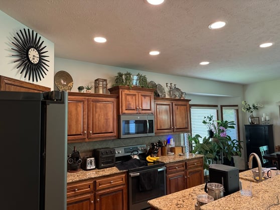 Kitchen with interior walls freshly painted off white with warm brown stained cabinets and stainless steel appliances.