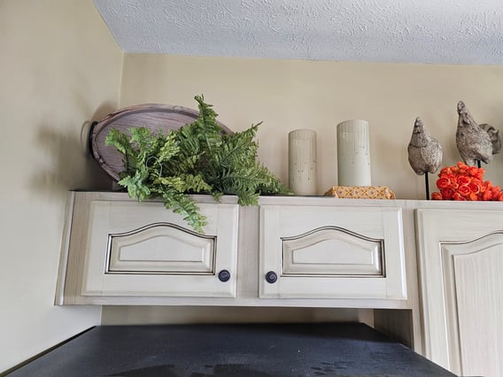 Upper cabinet doors above fridge in a kitchen painted white with light greige glazing overtop.