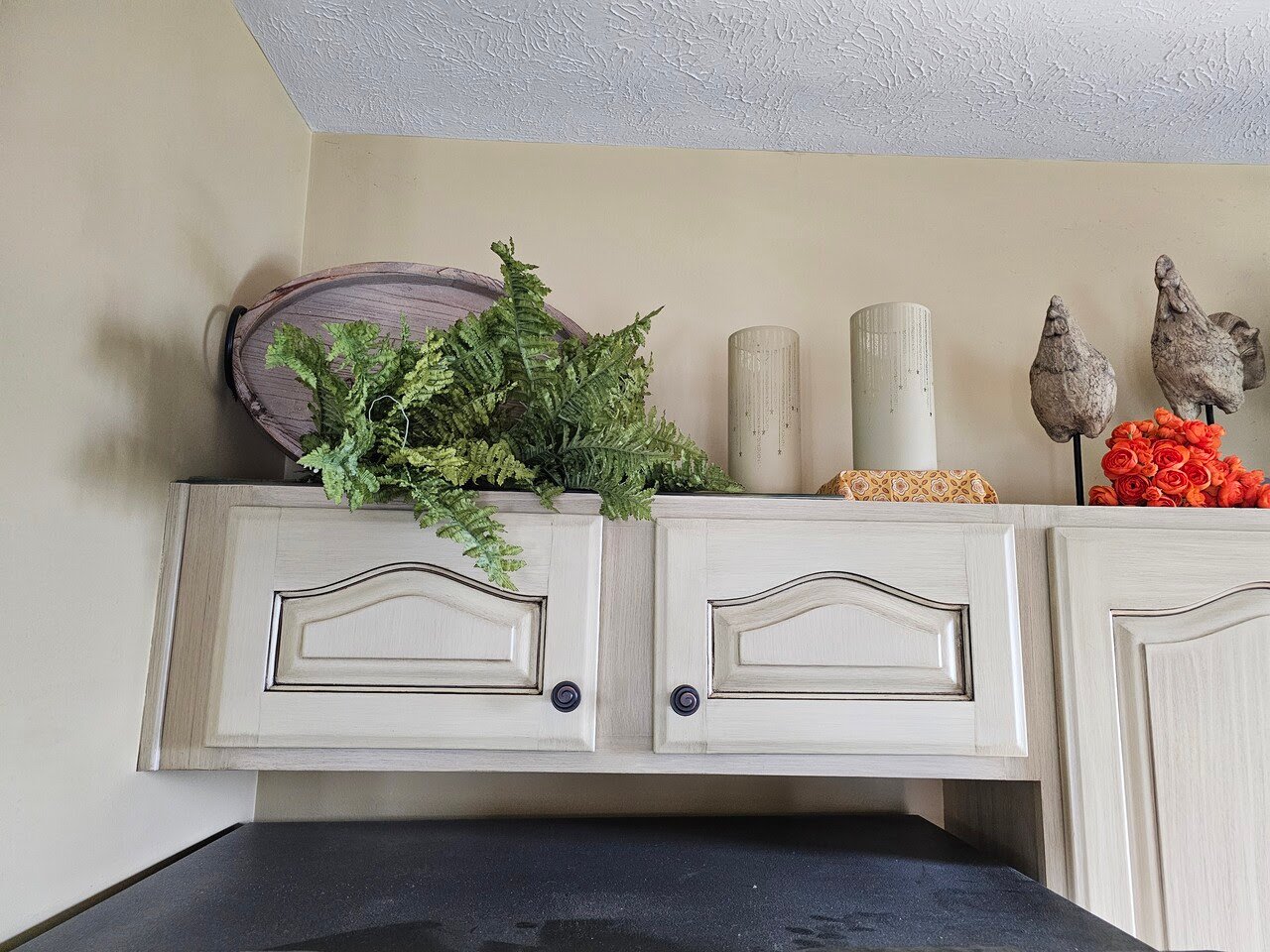 Painted upper kitchen cabinet doors in a white color with a glaze overtop to fill in the details and give a brushed look.