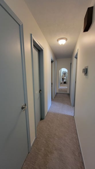 Hallway with trim and interior doors painted a soft baby blue color with white walls.