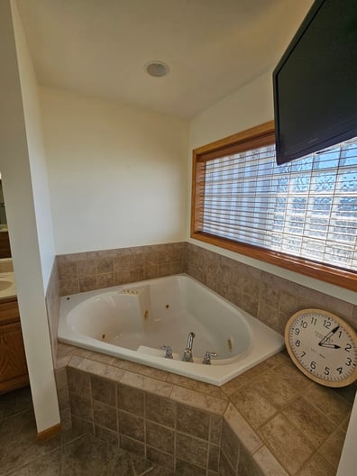 Bathroom walls painted white with a large tub with brown tile.