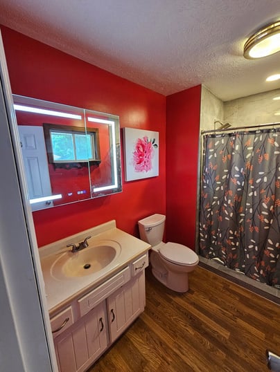 Bathroom with bright red walls and a white painted vanity.