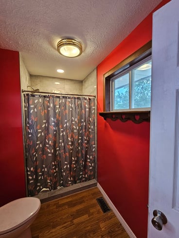 Bathroom with bold red walls and a matching shower curtain.