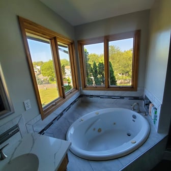 Bathtub and two windows with golden oak trim.