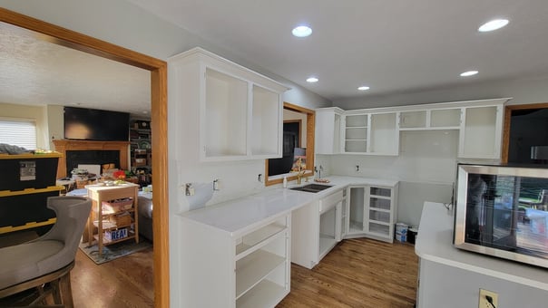 Kitchen with empty cabinets that have just been sprayed white.