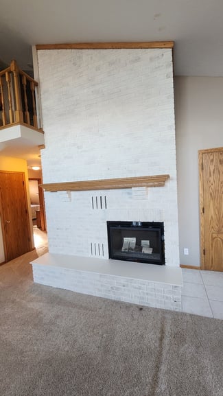 Limewashed white painted fireplace inside of a living room in Omaha, NE.