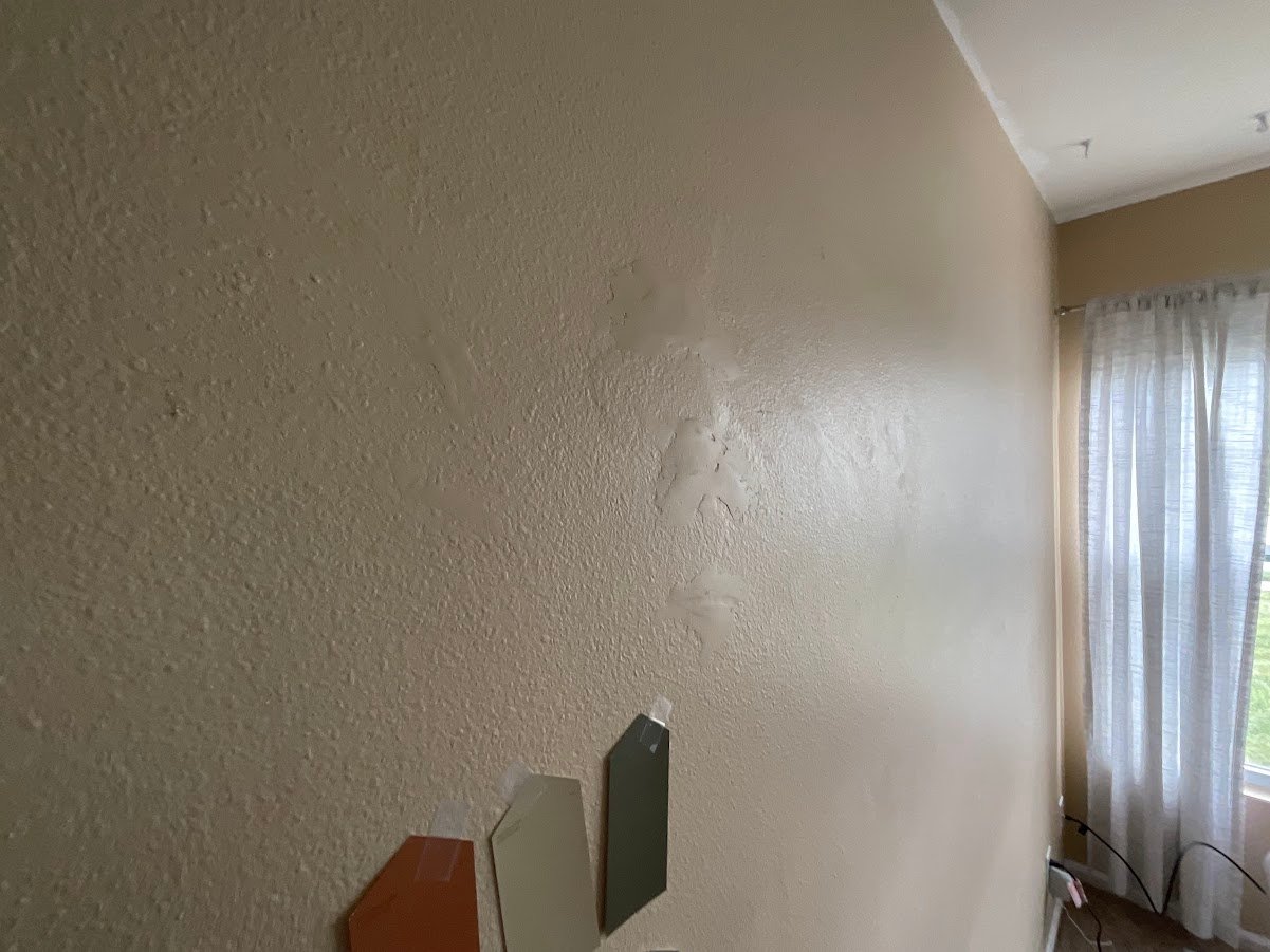 Wall with flashing paint spots and color samples taped on the wall.