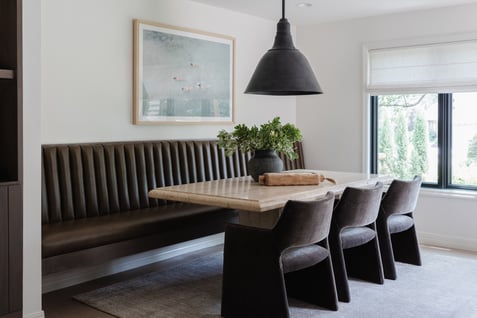 Dining room with white walls and black benches and chairs and lighting.