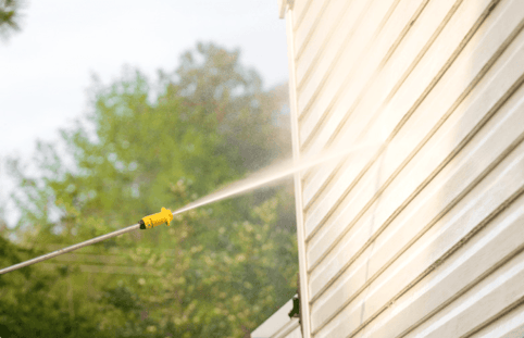 Power washer hitting exterior siding of a house with lead paint in Omaha, NE.