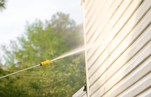 Power washing home with tan siding