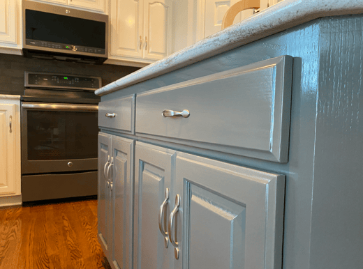 Sage green cabinet door and drawer with silver handles in kitchen.