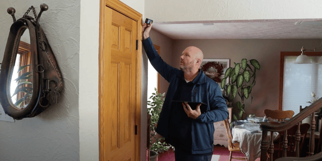 Owner of Brush & Roll Painting, Bill Carlson, measuring wooden oak door frames in a home.