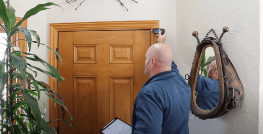 Owner of Brush & Roll Painting in Omaha, measuring the frame or casing around a wooden interior door.