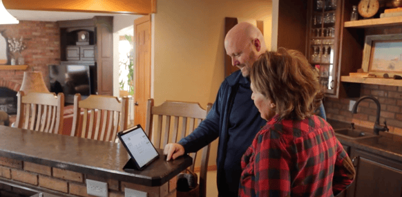 Bill Carlson, owner of Brush & Roll Painting, going over a painting estimate with a homeowner on an iPad at a countertop.