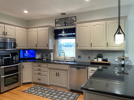 Kitchen with cabinets painted a off white beige shade with dark handles