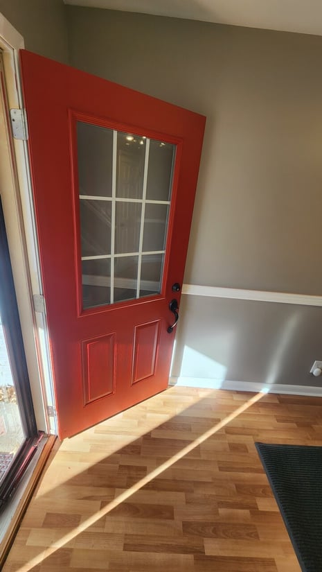 Door with a main window panel painted red with white trim.