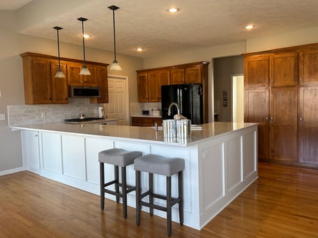 Warm wooden cabinets and floor matching with a white kitchen island in the center.