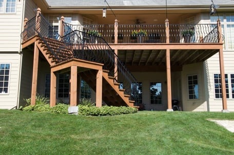 Backside of house with deck with a descending staircase stained warm brown.