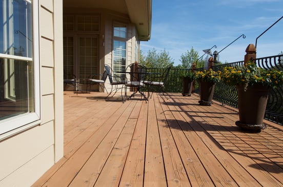 Freshly stained deck in Omaha with flower planters and outdoor furniture.