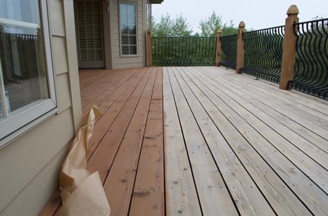 Wooden deck in the process of being stained with a deck staining product in a medium, warm brown shade.